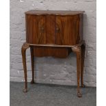 A walnut double bow front cabinet raised on tapering cabriole legs.