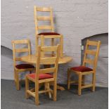 A circular centre pedestal light oak table, along with a set of four ladder back chairs, 170cm