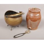 A glazed stoneware keg, along with a brass coal scuttle with tongs.