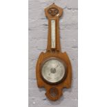 A large carved oak banjo barometer with silvered dial.