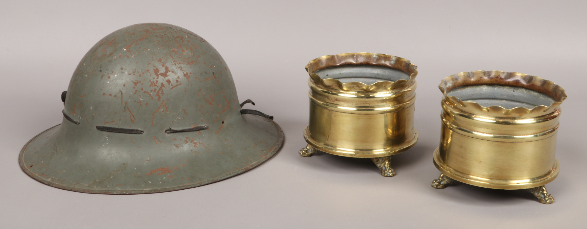 A 1941 World War II Tommy helmet, along with a pair of World War One trench art shell cases.