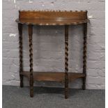 An oak demi lune side table with scalloped top and raised on barleytwist supports.