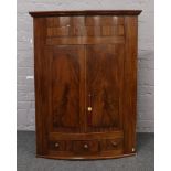 A Victorian mahogany barrel front corner cupboard with panelled doors and single drawer.
