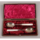 A cased pair of mother of pearl handle white metal spoons.
