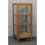 A light oak display cabinet with V shaped shelves, 146cm x 61cm x 52cm.