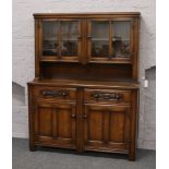 A carved and panelled oak dresser with glazed display.