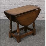 A carved and turned oak drop leaf occasional table.