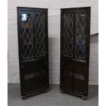 A pair of carved oak lead glazed comer cupboards, 168cm high.