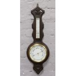 An early 20th century carved dark oak banjo barometer with porcelain dial.