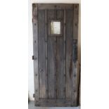 A studded panelled oak door with glass bulls eye panel and iron furniture, painted green to one