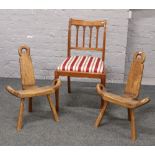 A pair of rustic carved oak milking stools along with a spade foot upholstered seat chair.