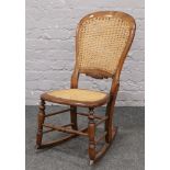 A Victorian rocking chair with canework seat and back rest.