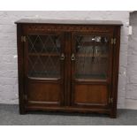 A carved oak lead glazed bookcase display cupboard.