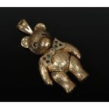 A 9ct gold novelty pendant formed as a teddy bear with jointed limbs, wearing a bow tie and gem set,