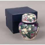 A boxed Moorcroft ginger jar and cover, decorated over a purple ground with winter berries, 11cm.