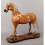 A 19th century pony hide mounted hobby horse on four wheeled pine plinth, 74cm high.