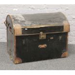 A black canvas dome top travel trunk with leather reinforced shoulders and internal tray.