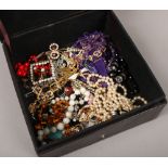 A leatherette box containing costume jewellery, beads and brooches.