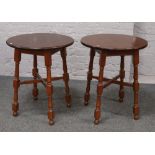 A pair of circular hardwood tavern tables raised on turned supports.