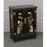 A Chinese black lacquered and hard stone set cabinet, decorated with flowers and birds with brass