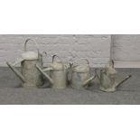 Four graduated galvanised steel watering cans.