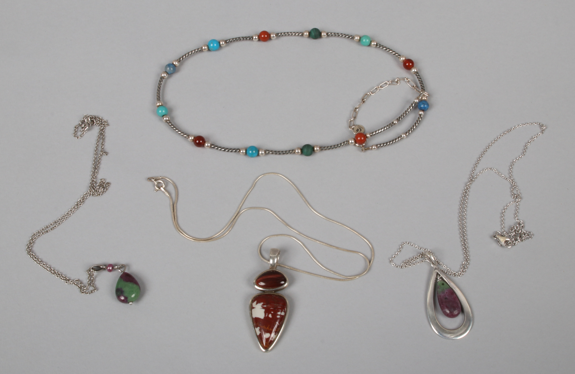 Four silver stone set necklaces and pendants on chain.