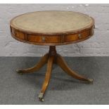 A rotating leather inset drum table, raised on brass lion paw feet.