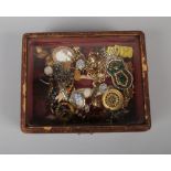 A glass top jewellery box containing vintage costume jewellery including gilt brooches, cufflinks,