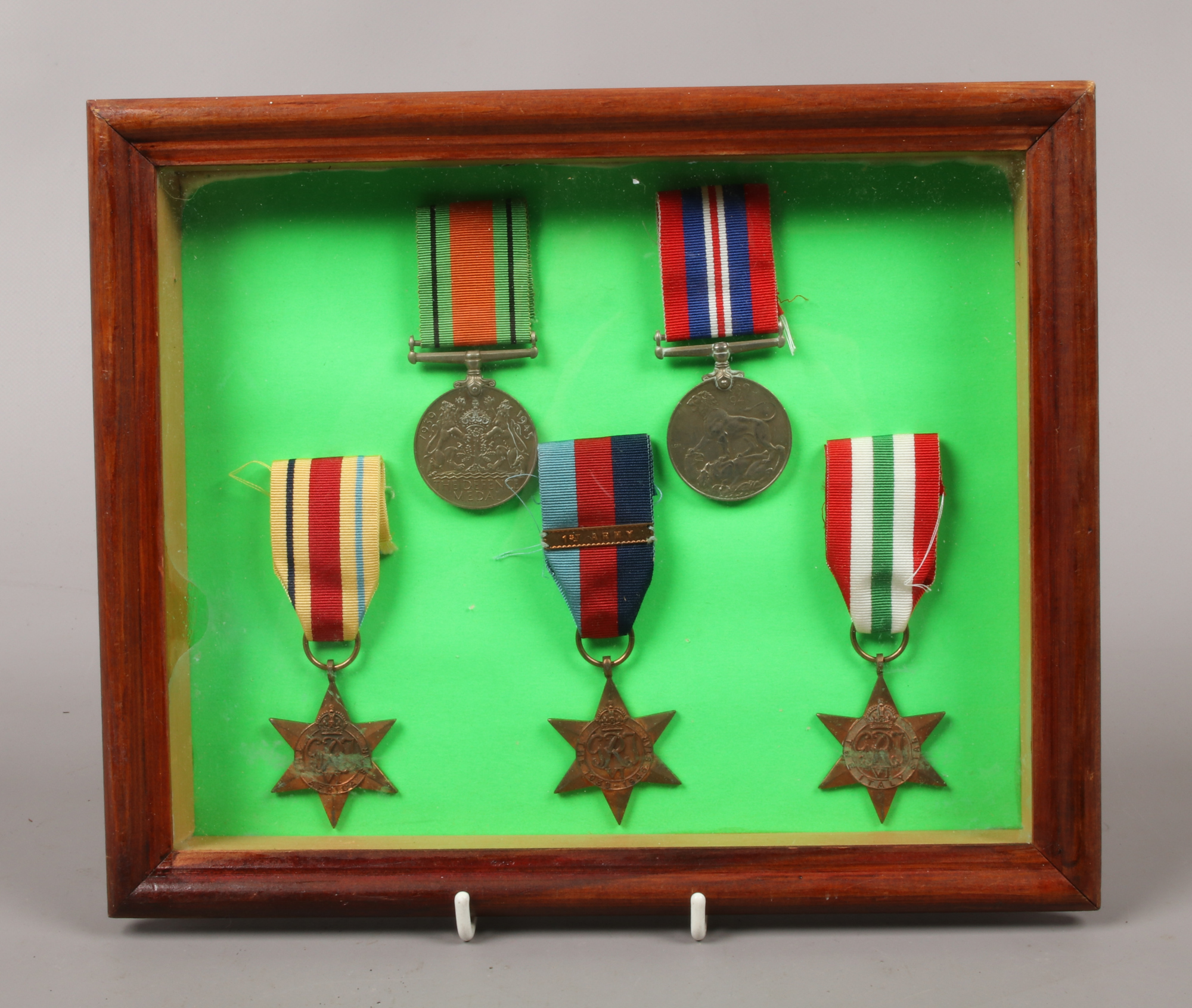 A framed set of five World War II medals on ribbons, including the Defence medal, War medal,