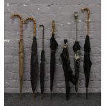 A collection of parasols / umbrellas to include white metal, carved wood and ebonised examples.