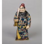 A Chinese figure formed as a bearded warrior wielding a sword. Wearing a long flowing robe and