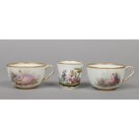 A pair of Sevres breakfast cups with gilt dentil rims and enamelled with Watteauesque scenes,