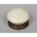 A Chinese circular paste pot and cover on associated hardwood base. With raised scroll mouldings and