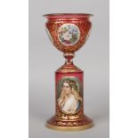 A 19th century Bohemian cranberry glass pedestal vase of urn form. With foliate gilding enamelled to