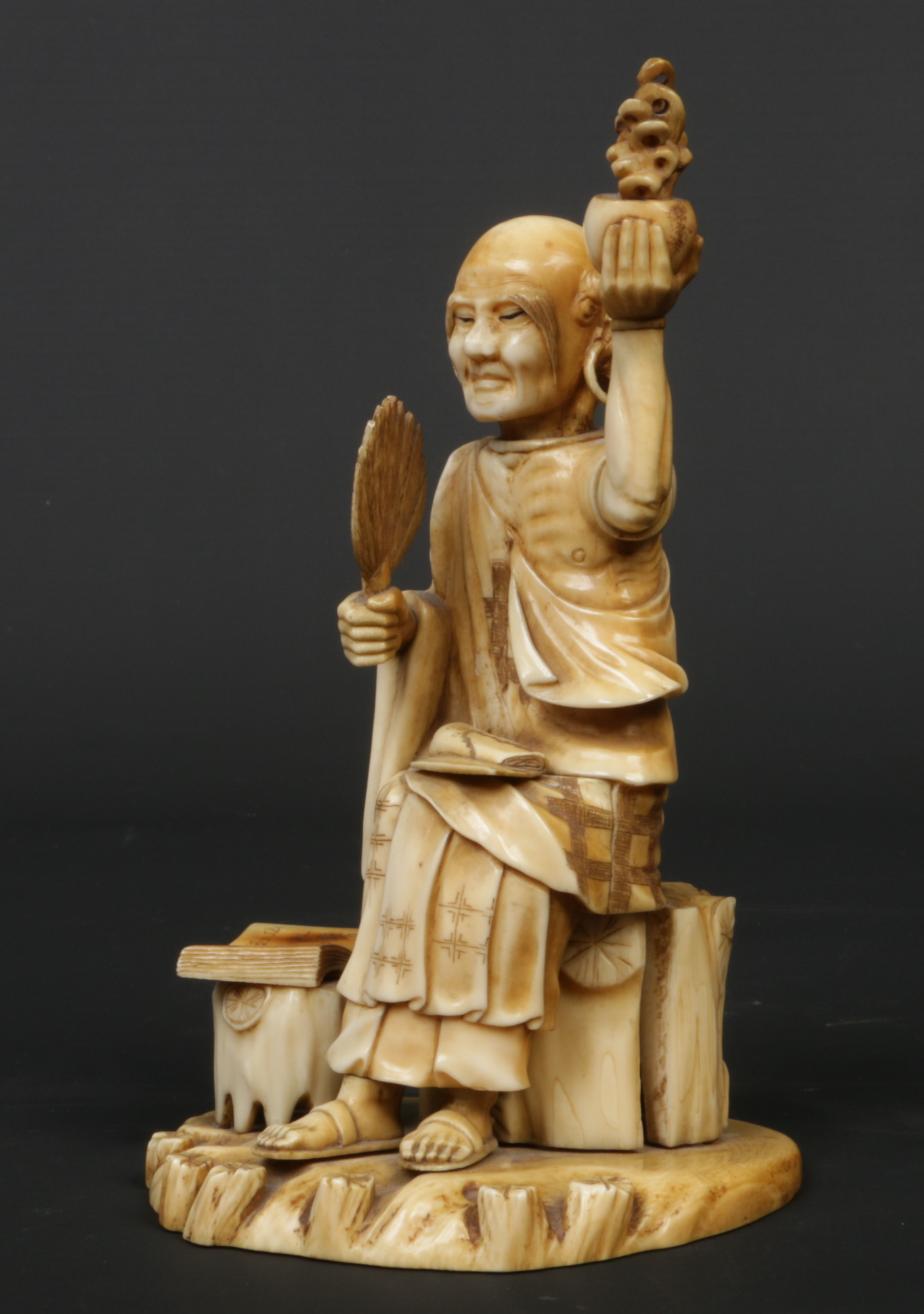 A Japanese Meiji period carved ivory okimono. Formed as a seated sage. Signed with a lacquer