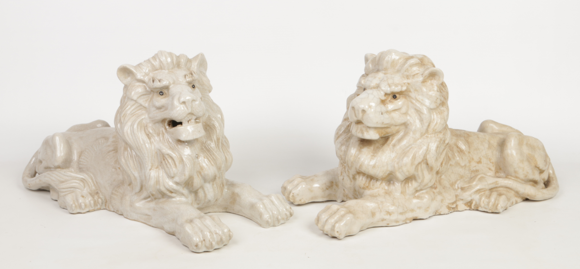 A pair of terracotta white crackle glazed models of recumbent lions. 58cm long. Condition report