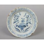 An 18th century Delft blue and white dish. Painted with flowers under a crescent border, 22.5cm