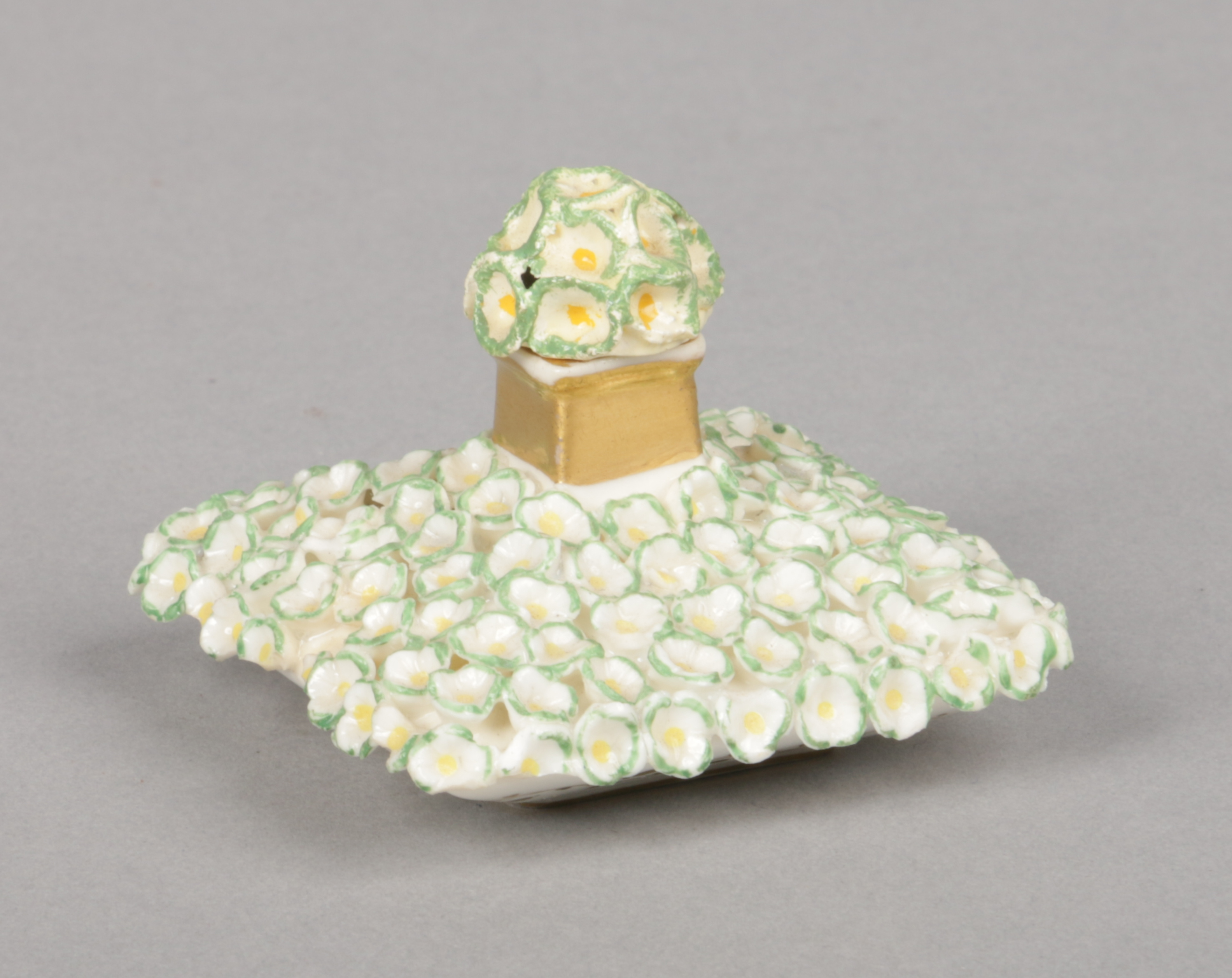 A rare Rockingham miniature diamond-shaped scent bottle. Encrusted with applied flower heads edged