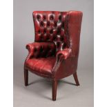 A mahogany and red leather deep buttoned porters chair raised on reeded square tapering supports,