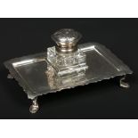 A silver mounted glass inkwell on associated stand. The rectangular stand with scalloped rim is