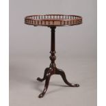A Georgian mahogany snap top wine table. The circular top with gallery is raised on a tapering
