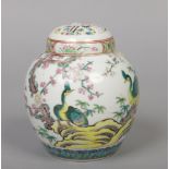 A Chinese polychrome ginger jar and cover. Painted with a pair of peacocks in a continuing landscape