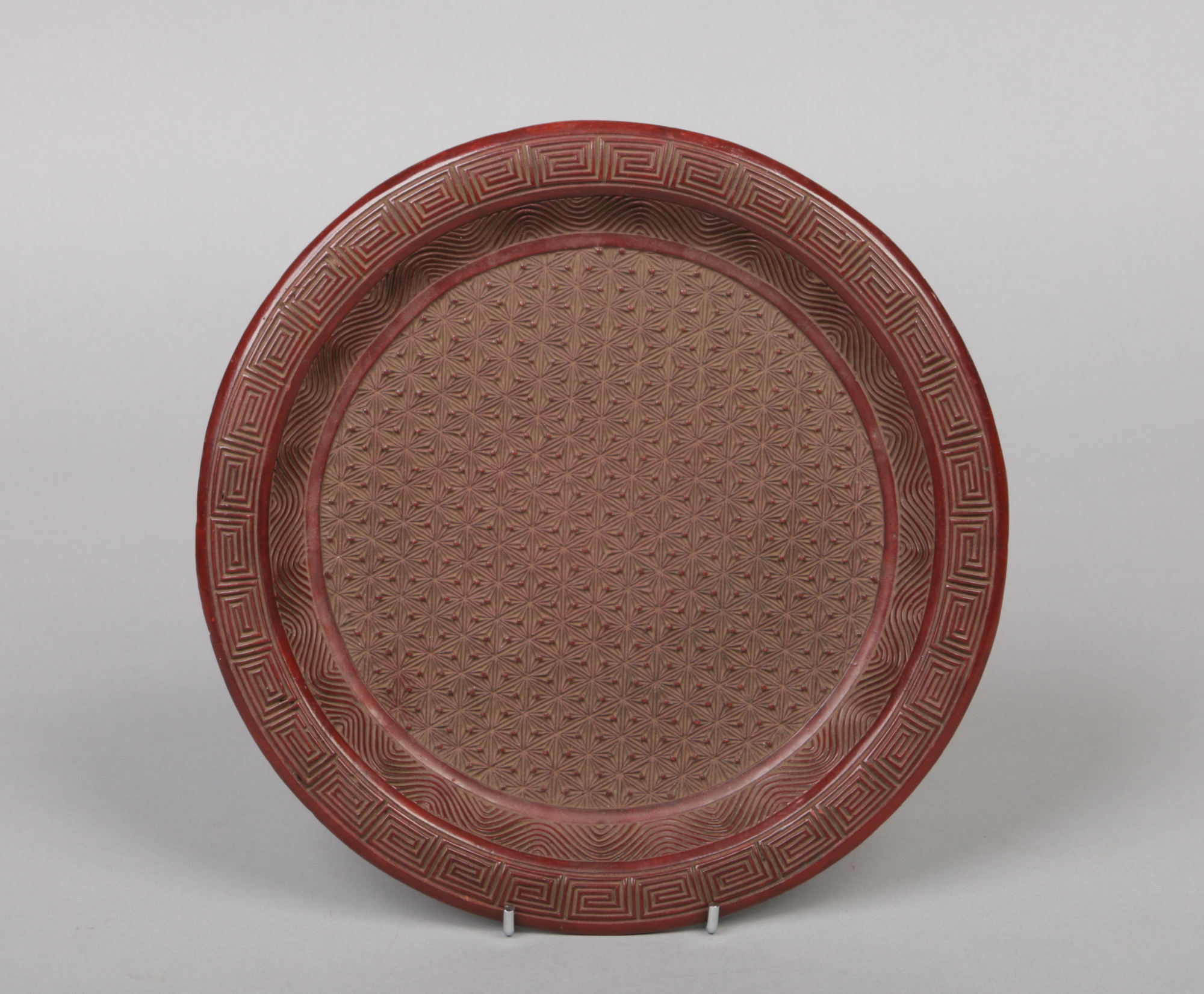 A Chinese cinnabar coloured lacquer dish. Moulded with a key fret border and a concentric ground