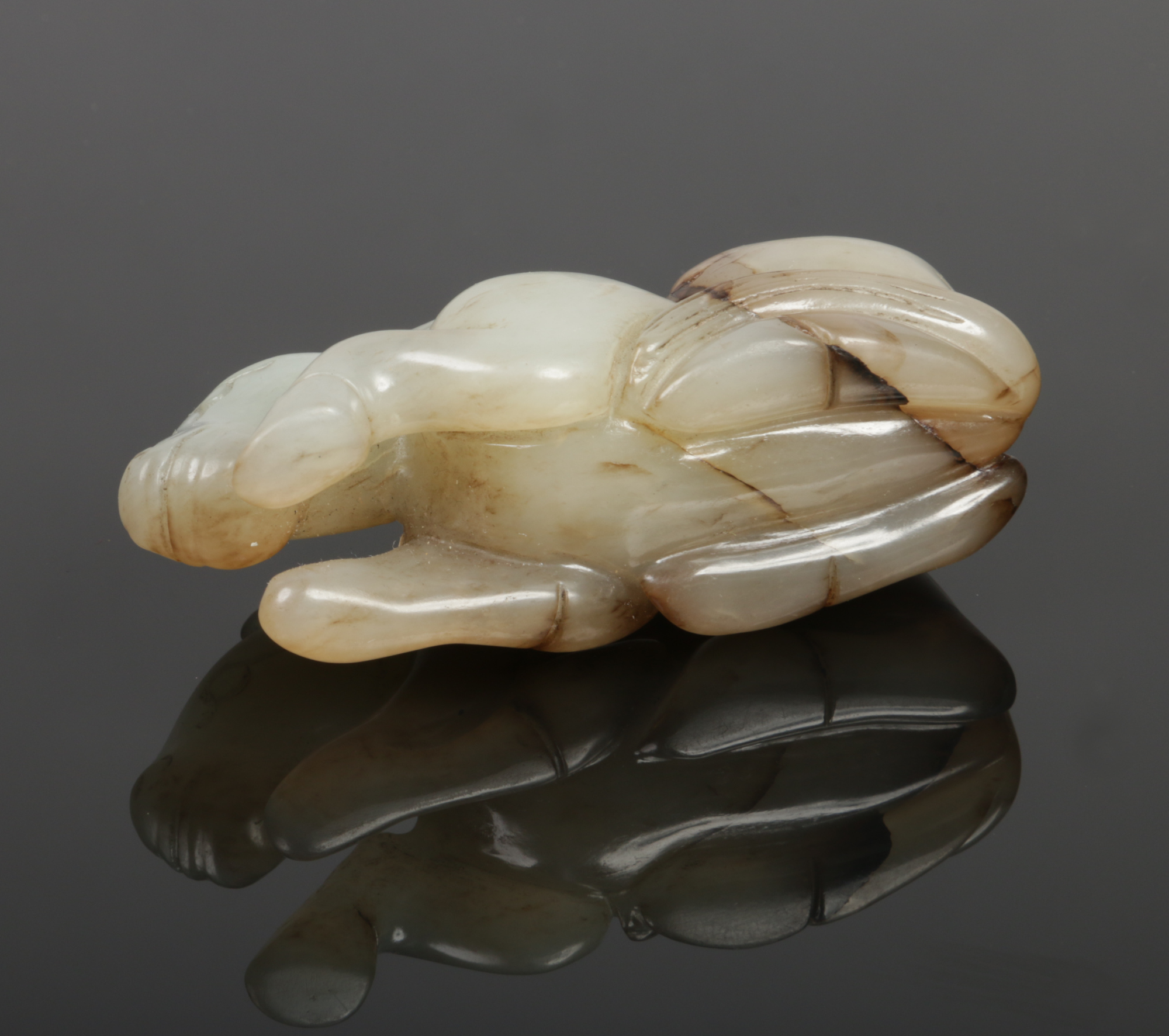 A Chinese carved pale celadon jade recumbent horse with dark brown suffusions, 7.75cm.Condition - Image 2 of 4