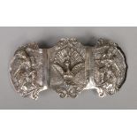 An Eastern white metal three panel buckle. Decorated in relief with a pair of figures and a