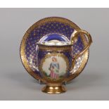 A 19th century Berlin cabinet cup and saucer with scrolling handle having unglazed mask and acanthus