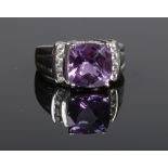 A 9 carat white gold dress ring set with a cushion cut amethyst with a band of four diamonds to each