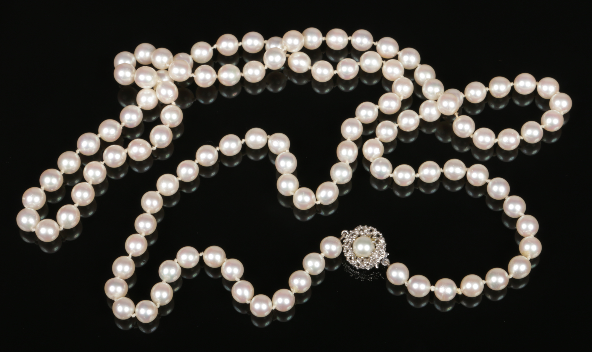 A long string of pearls with 14 carat white gold coral branch formed clasp. With 111 uniform pearls,