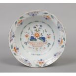 An 18th century polychrome delft bowl. Painted to the centre with a basket of flowers under a diaper