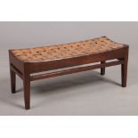 Arthur W. Simpson of Kendal, an Arts & Crafts oak double stool with lattice leather strap concave